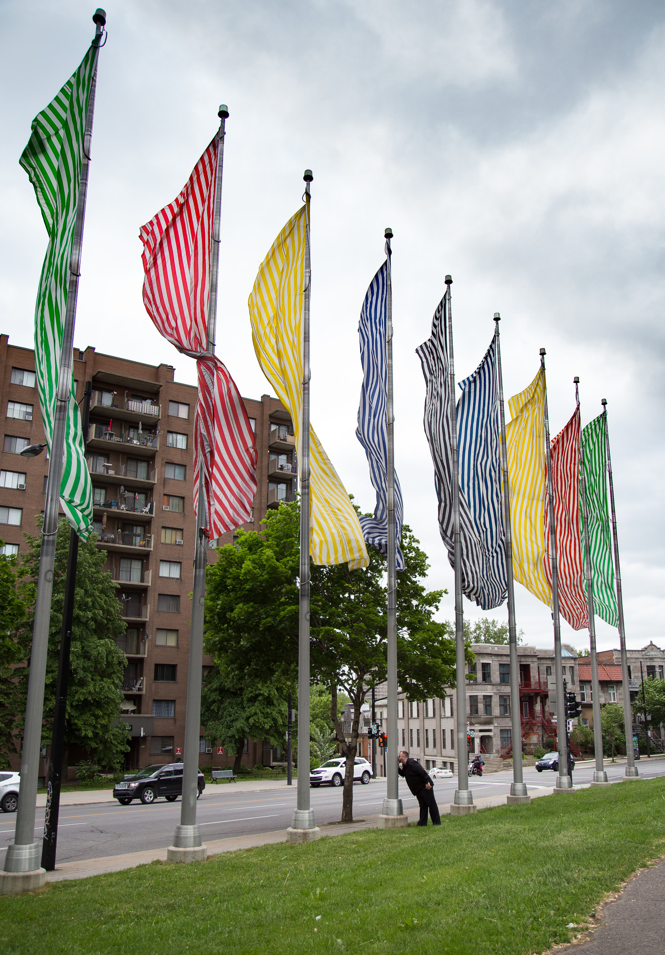 Steve Giasson. Performance invisible n&deg; 158 (Embrasser une&nbsp;&oelig;uvre d'art). Daniel Buren. Neuf couleurs au vent. 1984. Performeur : Steve Giasson. Cr&eacute;dit photographique : Daniel Roy. Place Urbain-Baudreau-Graveline, Montr&eacute;al. 13 juin 2016.