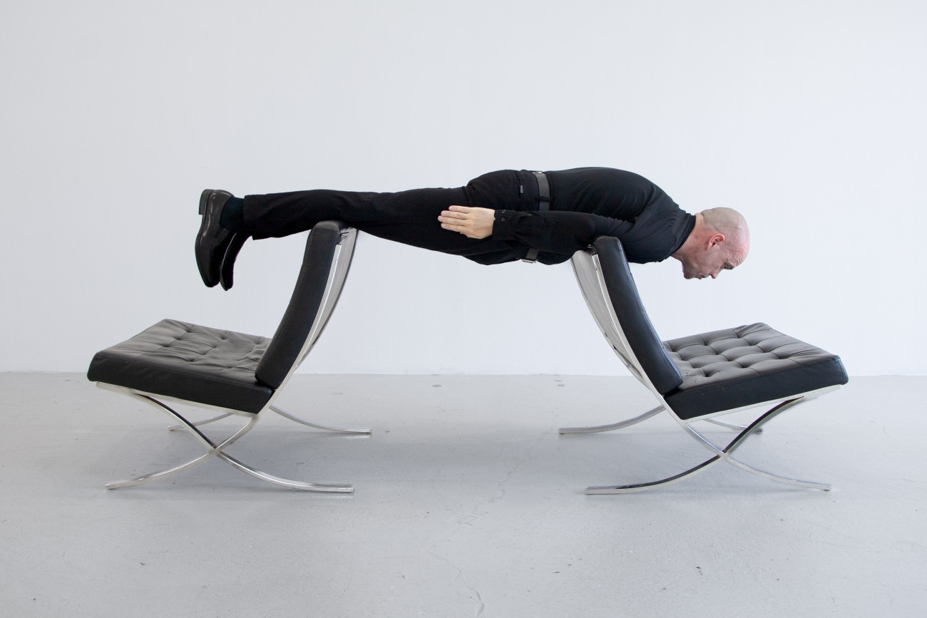 Steve Giasson. Performance invisible n&deg; 260 (Pr&eacute;dire le pass&eacute; / &Ecirc;tre absolument moderne). Reenactment de Erwin Wurm.&nbsp;Sigmund Freud modern (One Minute Sculpture).&nbsp;2005. Performeur : Steve Giasson. Cr&eacute;dit photographique : Martin Vinette. Retouches photographiques : Charles-&Eacute;tienne Lebrun. Galerie B-312. 9 ao&ucirc;t 2025.