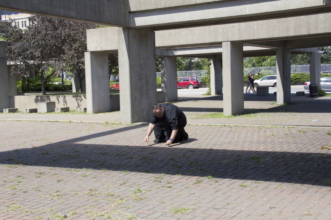 Steve Giasson. Performance invisible n° 9 (Insérer discrètement des bijoux dorés dans l'Agora de Charles Daudelin (Square Viger, Montréal).)) Performeur : Steve Giasson. Crédit photographique : Daniel Roy. 1er août 2015.
In "Actes de disparition", Square Viger, Montréal.